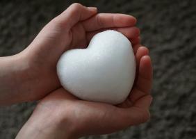 Photo of two hands hold a white heart