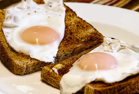 Two pieces of toast with eggs on them on a white plate