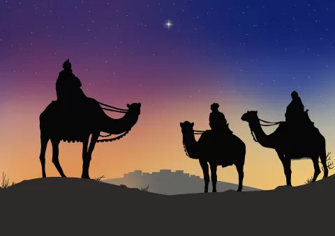 Three wise on camels standing in front of a sunrise sky