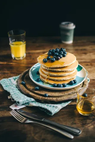 Stack of pancakes on a blue plate with blueberries on top
