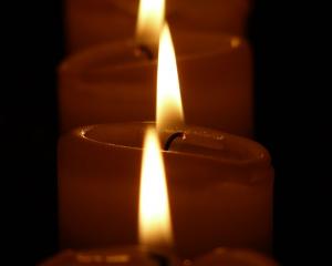three lit candles in a row in darkness